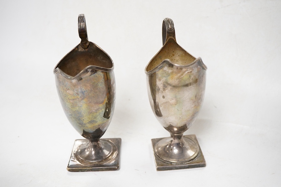 A George III silver helmet shaped cream jug, London, 1795, height 15cm, weighted, together with a later similar cream jug, Birmingham, 1962.